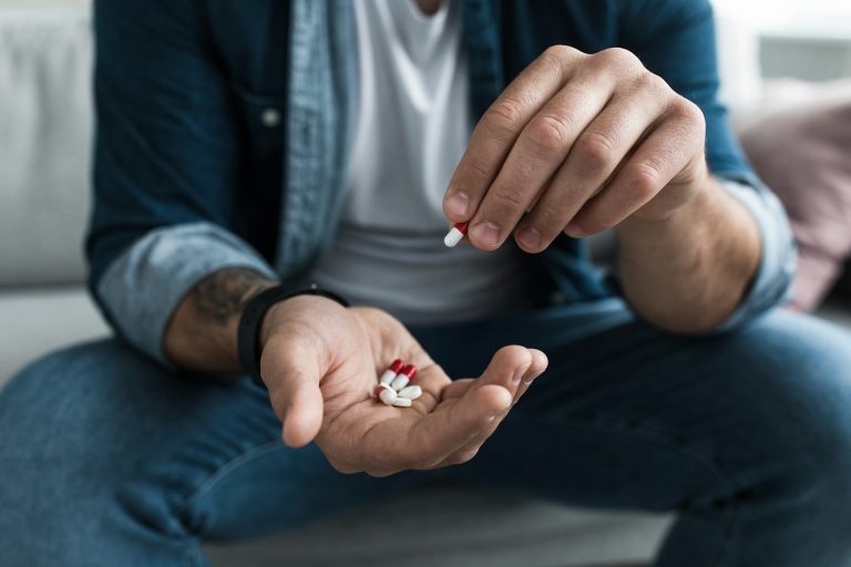 Colorful pharmaceutical medicine pills, narcotic drugs in capsules on palm