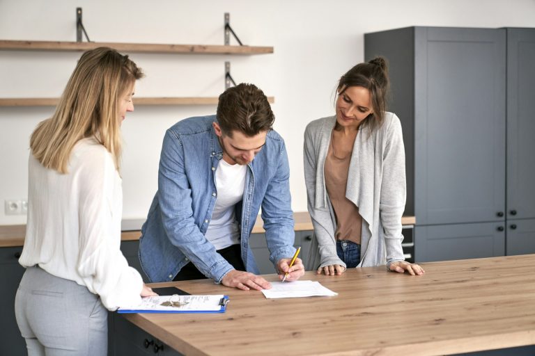 Young caucasian couple signing house purchase agreement with a real estate agent